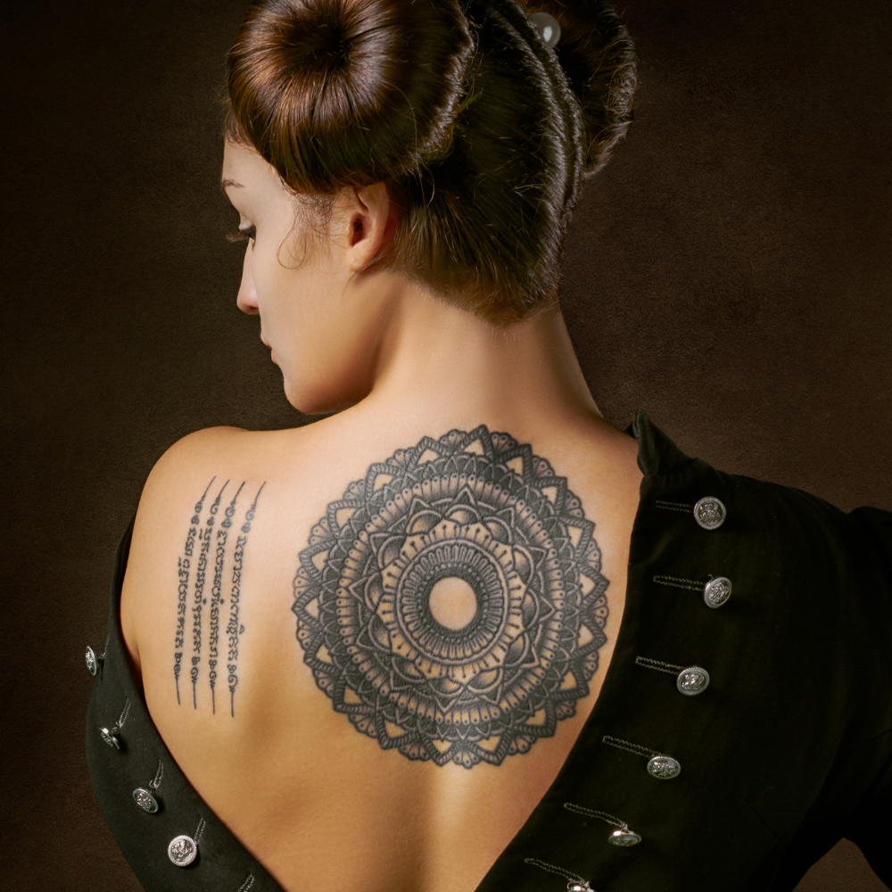 woman's back with large circular tattoo and vertical writing